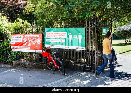 Une femme qui entre dans un parc pour faire de l'exercice par une journée ensoleillée pendant le confinement en cas de pandémie du coronavirus, conseils sur la distanciation sociale aux portes, Londres, Royaume-Uni Banque D'Images