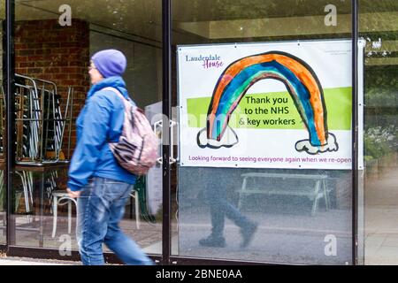 Une femme qui marche devant un avis remerciant le NHS et les principaux travailleurs de Lauderdale House, Waterlow Park, fermée pendant le confinement du coronavirus, Londres, Royaume-Uni Banque D'Images