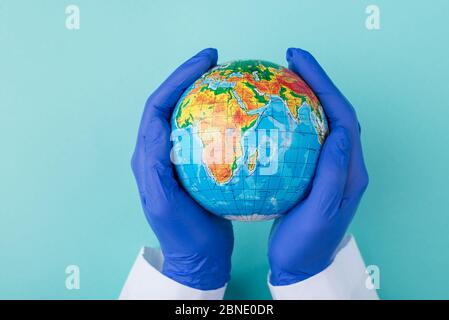 Haut au-dessus de la tête vue rapprochée photo d'un globe dans les mains du médecin isolé sur fond turquoise Banque D'Images