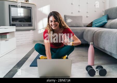 femme faisant du sport sur un tapis suivant des cours en ligne avec un ordinateur portable à la maison Banque D'Images