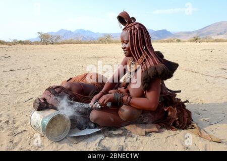 Les femmes Himba tressage de cheveux de l'autre. La vallée de Marienfluss. La Namibie Kaokoland, Octobre 2015 Banque D'Images