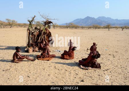 Les femmes Himba sont assises ensemble à côté de la cabane temporaire, dans la vallée de Marienfluss. Kaokoland, Namibie. Octobre 2015 Banque D'Images