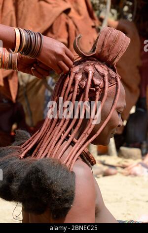 Les femmes Himba se bradant les cheveux de l'autre. Notez l'ornement traditionnel de tête connu sous le nom de 'Erembe', indiquant qu'elle est mariée, Kaokoland, Namibie octobre Banque D'Images