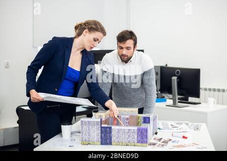 Les jeunes employés du bureau d'architecte discutant du mod de construction Banque D'Images