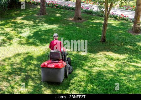 Vue de dessus du haut de la tondeuse professionnelle coupe de l'herbe verte fraîche avec machine tracteur de récolte de terrain dans le parc de la ville. Jardin et Banque D'Images