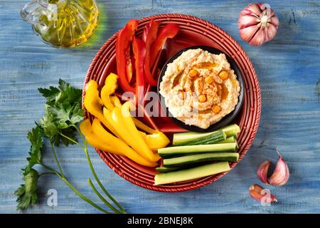 Gros plan d'un plateau rouge vif et coloré de légumes frais assortis avec sauce houmous Banque D'Images