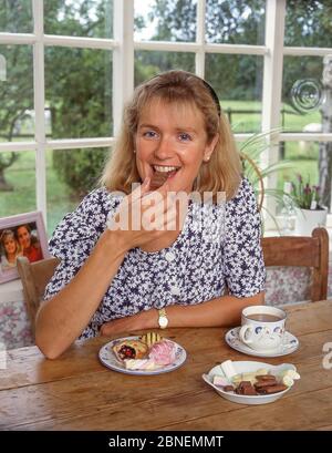 Jeune femme avec une tasse de thé avec des gâteaux et des bonbons, Winkfield, Berkshire, Angleterre, Royaume-Uni Banque D'Images