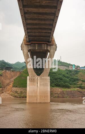 Huangqikou, Chongqing, Chine - 8 mai 2010 : fleuve Yangtze. 1 des 2 pylônes en forme de losange vus sous le pont de suspension G319. Eau brune et vert Banque D'Images