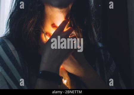 Femme stressée avec une lumière qui brille vers le bas de sa gorge avec une montre intelligente Banque D'Images