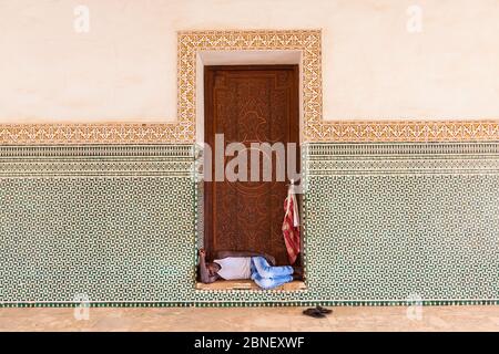 Homme sans-abri dormant dans une porte. grande mosquée magnifique ornement porte en bois Banque D'Images