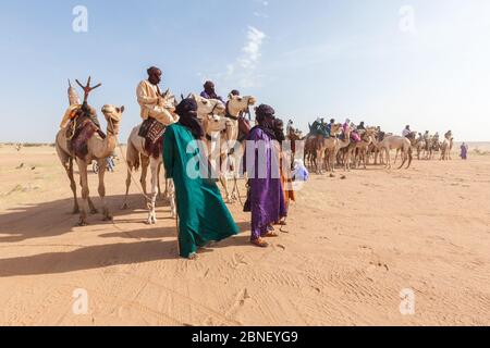 Ingall, Nige Curee Vente festivalr: tuareg gens dans des vêtements traditionnels assis sur des chameaux dans le désert Banque D'Images