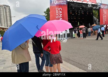 Les gens se rassemblent sous la pluie au parc commémoratif Thomson, à Toronto, pour assister aux spectacles de la fête du Canada. Banque D'Images