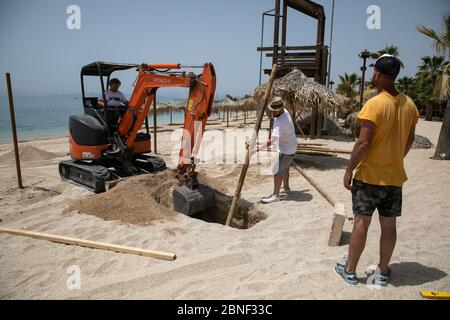 Athènes, Grèce. 14 mai 2020. Les travailleurs installent un parapluie sur la plage organisée d'Alimos, au sud d'Athènes, en Grèce, le 14 mai 2020. Les autorités grecques ont annoncé mercredi qu'à partir de mai 16, les 515 plages organisées du pays s'ouvriront sous des restrictions afin d'éviter la surpopulation. Le ministère grec de la Santé a signalé jeudi que le nombre d'infections par le COVID-19 a atteint 2,770 et que 156 décès ont été enregistrés depuis le début de l'épidémie dans le pays le 26 février. Crédit: Lefteris Partsalis/Xinhua/Alay Live News Banque D'Images