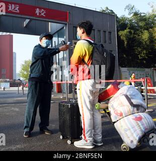 Les élèves prennent une température avec leurs bagages désinfectés tout en revenant à l'école après deux et demi de vacances d'hiver dans une école secondaire locale, Bozh Banque D'Images