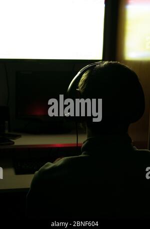 Vue arrière d'un homme jouant à des jeux vidéo avec un casque Banque D'Images