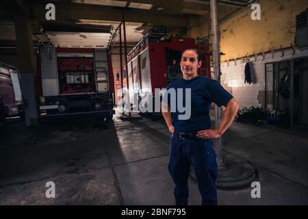 Portrait d'une pompier féminine se tenant contre un camion de pompiers à la station Banque D'Images