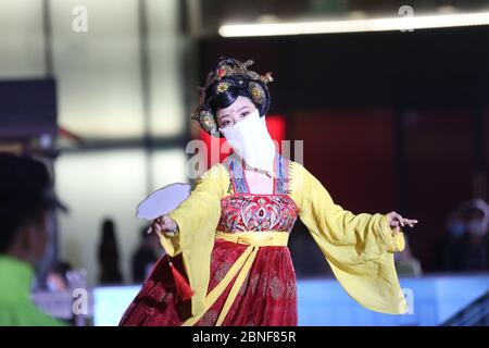 La Tumbler Girl, danseuse d'une attraction touristique locale appelée Grand Tang Dynasty Ever Bright City, se produit pour les touristes avec masque facial sur, Xi'an ci Banque D'Images