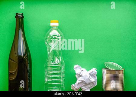 déchets, écologie, tri des déchets concept - disposition du tri des déchets en 4 types: verre, plastique, papier, métal sur un fond vert copie espace. Banque D'Images