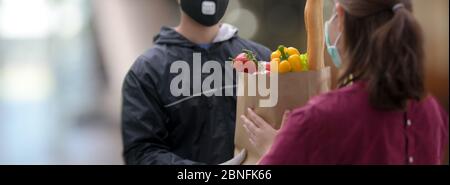 Photo de l'homme du service de livraison qui a remis le sac d'aliments frais à une cliente Banque D'Images