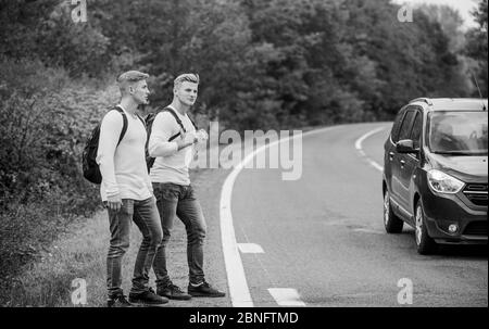 Geste de randonnée. Commencez une grande aventure dans votre vie avec la randonnée pédestre. Compagnie amis voyageurs qui déchire à la route nature fond. Voyageurs en route. Des amis qui voyagent avec des hitchhikers. Banque D'Images