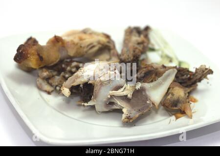 Gros plan d'os de poulet et de restes dans une assiette isolé sur fond blanc Banque D'Images