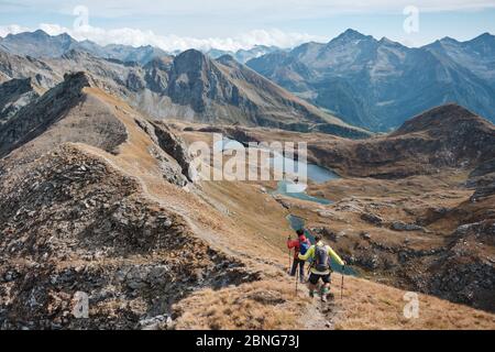 Deux hommes marchant sur un sentier panoramique dans les alpes avec des lacs comme arrière-plan dans une journée ensoleillée d'automne Banque D'Images