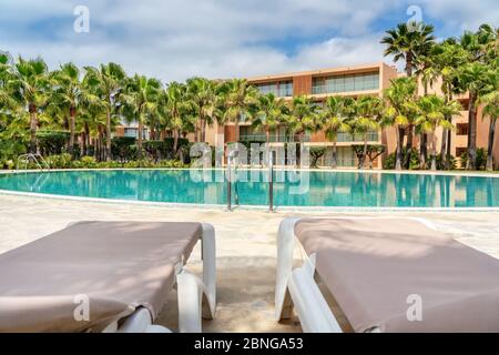 Piscine luxueuse et moderne avec eau claire et bleue et chaises longues sur place. Banque D'Images