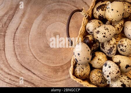 Œufs de caille dans un panier en osier sur texture coupée en bois. Œufs de caille de style rustique. Concept joyeuses pâques. Concept d'alimentation saine. Produit naturel biologique de Banque D'Images