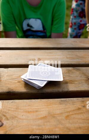 gros plan d'une pile de cartes à jouer sur un table de pub en bois avec un jeune garçon assis dans le arrière-plan en attente de lecture Banque D'Images