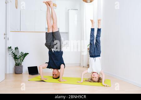 Yoga familial à la maison sur un tapis. Papa et fils faisant des chevets sans aide Banque D'Images