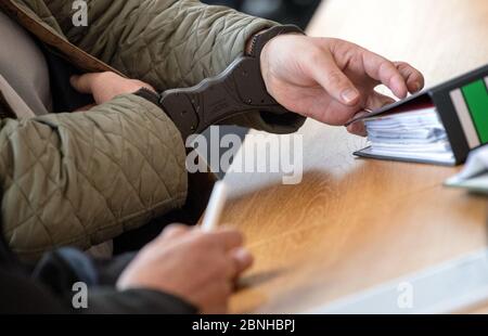 Stuttgart, Allemagne. 15 mai 2020. L'accusé, dans un procès pour fraude, porte des menottes et place un dossier à sa place dans une salle d'audience du tribunal de district. L'ancien chef de la coopérative d'habitation de Geno, en tant que responsable de la coopérative déjà insolvable, aurait trompé de nouveaux membres et les aurait fait payer un total de plus de deux millions d'euros. Credit: Marijan Murat/dpa/Alay Live News Banque D'Images