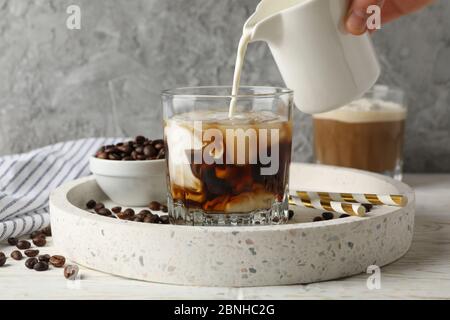Une femme verse un lait dans un verre de café. Composition avec café glacé Banque D'Images