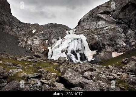 Paysage de chute d'eau avec neige dans la vallée de montagne contre ciel nuageux dans le parc national de Karakol, Kirghizistan Banque D'Images