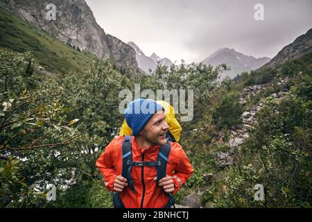 Portrait de touriste heureux avec grand sac à dos est dans la vallée de montagne du parc national de Karakol, Kirghizistan Banque D'Images