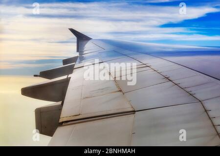 Aile d'une plaine aérienne en alliage léger contre le ciel bleu haut dans l'atmosphère terrestre - l'industrie du voyage longue distance et l'aviation. Banque D'Images
