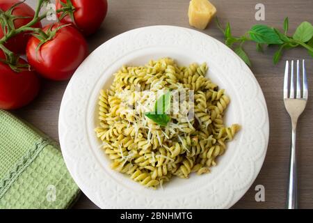 Pâtes italiennes traditionnelles végétariennes fusilli avec basilic frais maison et sauce pesto aux pignons et nappées de parmesan râpé. Tomate, basilic, Banque D'Images