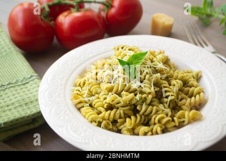 Pâtes italiennes traditionnelles végétariennes fusilli avec basilic frais maison et sauce pesto aux pignons et nappées de parmesan râpé. Tomate, basilic, Banque D'Images