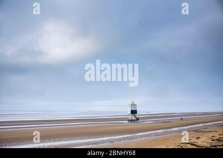 Une personne marchant sur la plage de sable du bord de mer en profitant de la solitude du canal de Bristol à Burnham-on-Sea, Somerset, Royaume-Uni Banque D'Images