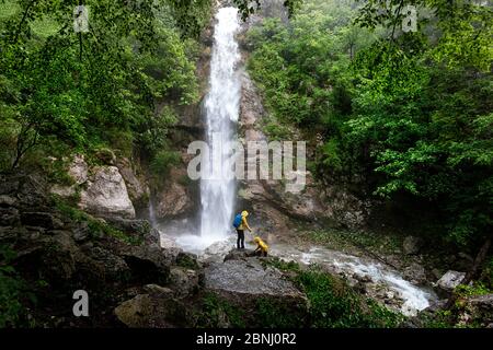 Vue arrière de mère et fils debout sur un rocher par une cascade dans la forêt Banque D'Images