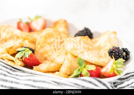 Des crêpes pliées en triangles et garnir de fruits rouges sur une assiette de service. Banque D'Images