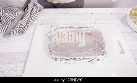 Étape par étape. Coupe de fudge de canne à sucre fait maison sur un tableau de découpe blanc. Banque D'Images
