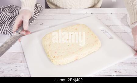 Étape par étape. Coupe de fudge de canne à sucre fait maison sur un tableau de découpe blanc. Banque D'Images