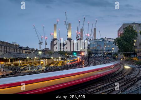 Longue exposition de train de voyageurs se rendant à la station électrique de Battersea, Londres, Angleterre, Royaume-Uni, Europe Banque D'Images