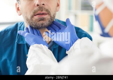 Gros plan du médecin en gants de protection examinant la gorge du patient pendant sa visite Banque D'Images
