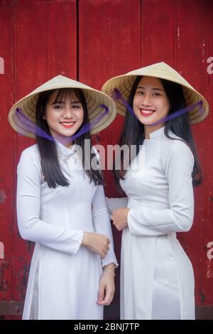 Deux jeunes femmes en robe traditionnelle debout à la porte occidentale de la Cité interdite pourpre, Hue, Vietnam, Indochine, Asie du Sud-est, Asie Banque D'Images