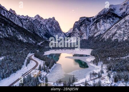 Lever de soleil sur le lac glacé Dobbiaco et les bois en hiver, Dobbiaco, Val Pusteria, Dolomites, province de Bolzano, Tyrol du Sud, Italie, Europe Banque D'Images
