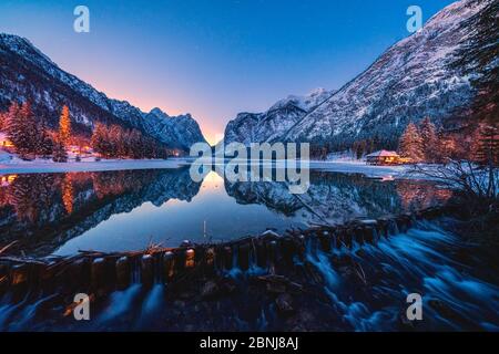 Lumières de crépuscule sur les sommets enneigés se reflétaient dans le lac Dobbiaco, Val Pusteria, Dolomites, province de Bolzano, Tyrol du Sud, Italie, Europe Banque D'Images