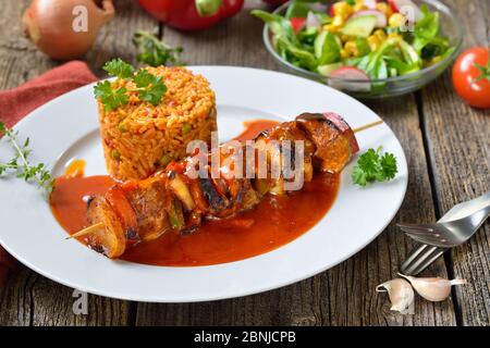 Brochette de shashlik généreuse dans une sauce épicée avec riz Djuvec et salade d'accompagnement mixte Banque D'Images