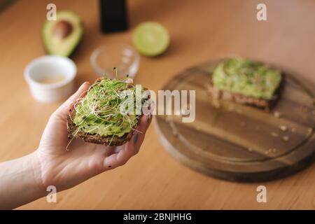 Vue de dessus de la femme tenir le pain de pain de seigle avec guacamole sur le dessus. Sans gluten Banque D'Images