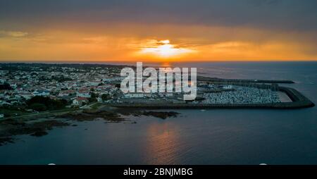 Un coucher de soleil chaud et nuageux fait face au port de la magnifique île d'Yeu en France, sur la côte ouest Banque D'Images